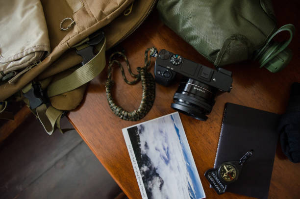 istock Hiking accessories set on wooden background with bag camera postcard glasses compass 810561348