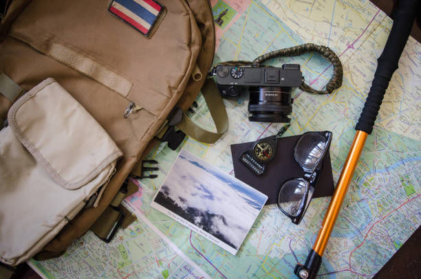 istock Hiking accessories set on wooden background with bag camera postcard glasses compass 810561400