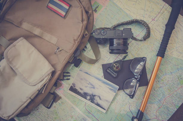 istock Hiking accessories set on wooden background with bag camera postcard glasses compass 810561532