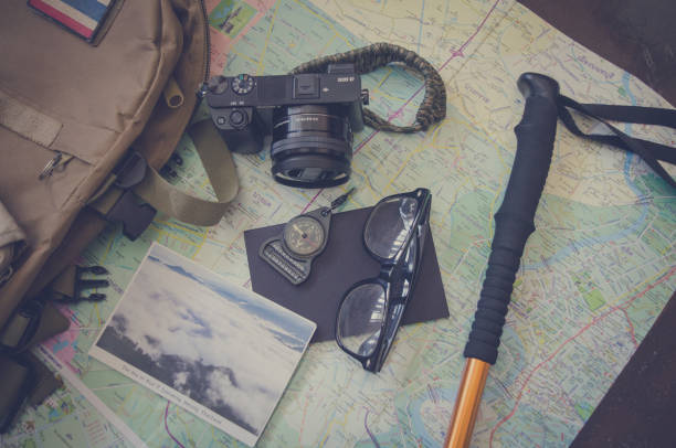 istock Hiking accessories set on wooden background with bag camera postcard glasses compass 810563670
