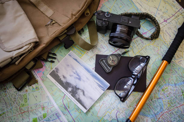 istock Hiking accessories set on wooden background with bag camera postcard glasses compass 810563740