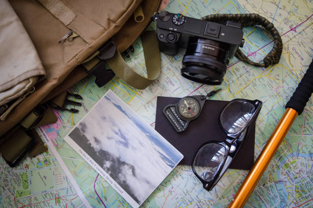 istock Hiking accessories set on wooden background with bag camera postcard glasses compass 810563834
