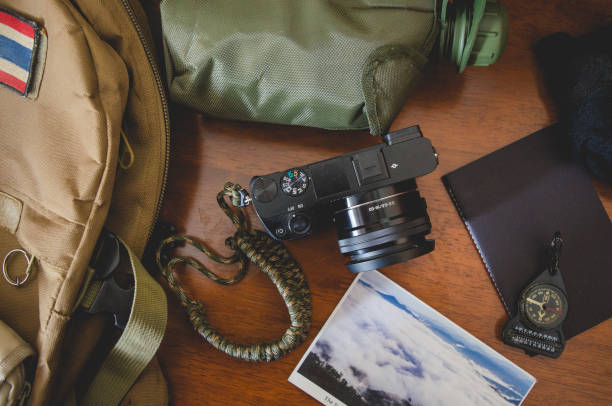 istock Hiking accessories set on wooden background with bag camera postcard glasses compass 810564262