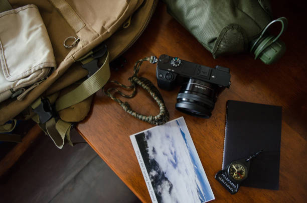 istock Hiking accessories set on wooden background with bag camera postcard glasses compass 810564440