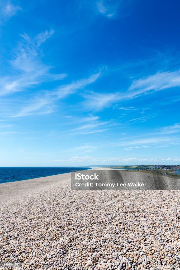 Chasil Beach and marina on Isle of Portland, England, aerial view Low wide angle view on Chesil Beach on Isle of Portland, UK. Blue clear sky and azure water. Vertical crop Beach Stock Photo