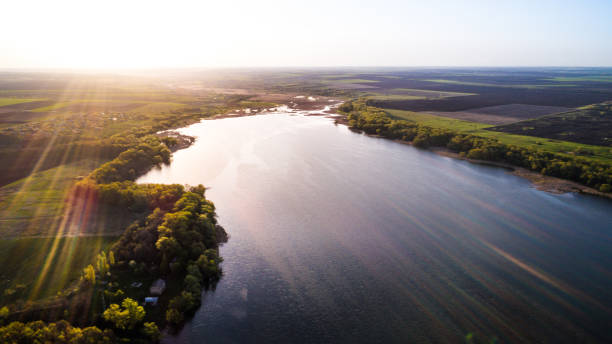 istock Aerial: Flying over a lake with sun illuminating the water. 810567510