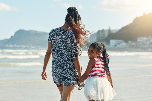 Portrait of a little girl enjoying a walk along the beach with her mother