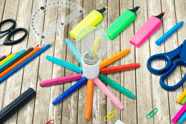 Closeup of multicolored school supplies with a light bulb on the wooden table