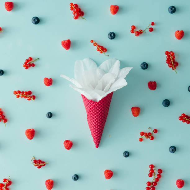 istock White flower in ice cream cone with forest fruit pattern. Flat lay. Summer concept. 810576210
