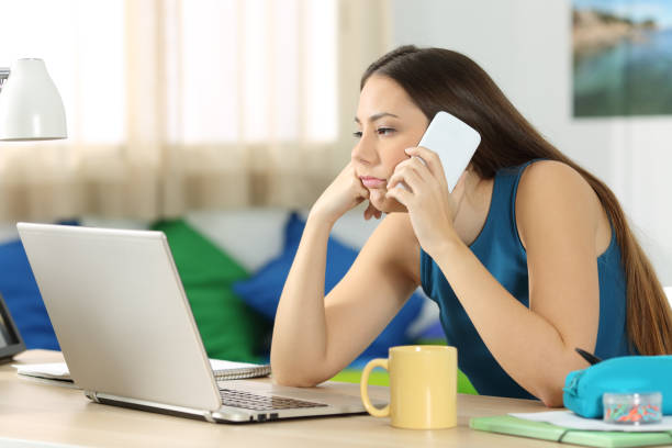 Bored student waiting in a phone call Bored student waiting during a phone call in a desk in her room waiting telephone on the phone frustration stock pictures, royalty-free photos & images