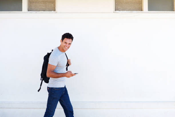 istock happy man walking with mobile phone and bag 810599094