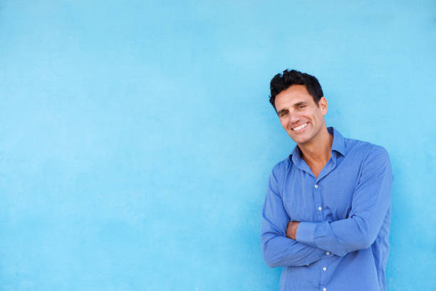 istock smiling businessman leaning against blue wall 810599108