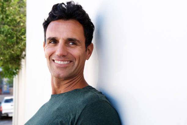 istock Close up handsome man leaning against wall and smiling 810599124