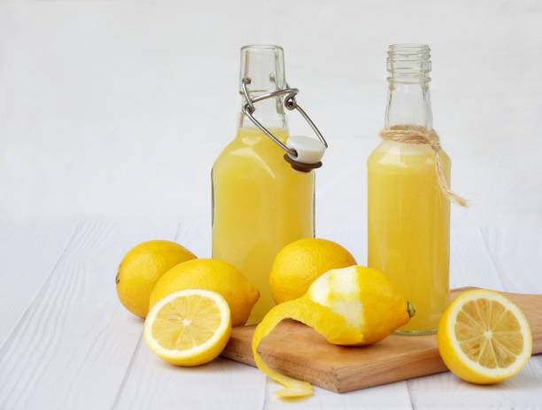 istock Freshly squeezed lemon juice in bottle and lemons on light background. For vitamin drink or cocktail. Selective focus. Space for text. 810603636