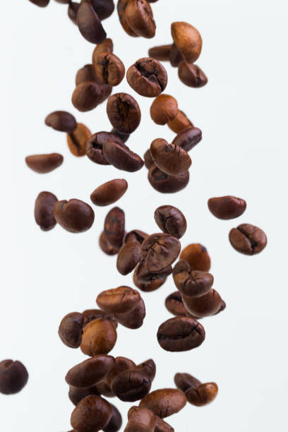 istock Falling grains of roasted coffee on a white background 810629868