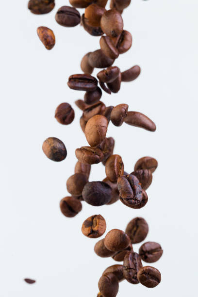 istock Falling grains of roasted coffee on a white background 810632034
