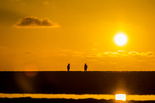 two people facing each other on beach in golden light at sunset