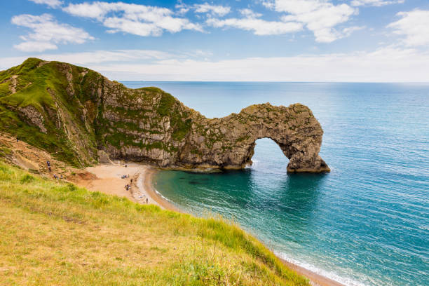 Durdle Door, travel attraction on South England, Dorset Durdle Door, travel attraction on South England, Dorset in sunny summer day with calm azure sea and blue sky. View from top of cliffs. durdle door stock pictures, royalty-free photos & images