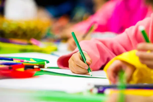 Hand of a child drawing a pencil on paper, part of the body