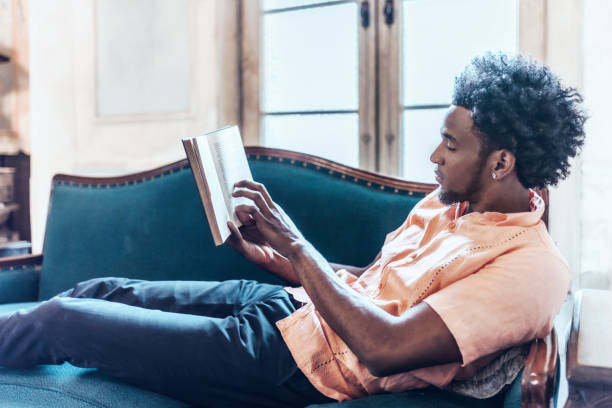 istock young afro-caribbean cuban reading book on sofa 810671274