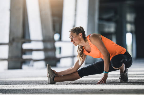 Female Athlete Stretching Outdoors Female Athlete Stretching Outdoors warm up exercise stock pictures, royalty-free photos & images