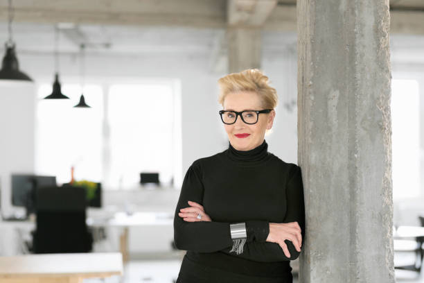 Portrait of elegant senior businesswoman in the modern studio Portrait of elegant senior businesswoman standing in the modern studio, smiling at the camera. middle aged woman fashion stock pictures, royalty-free photos & images