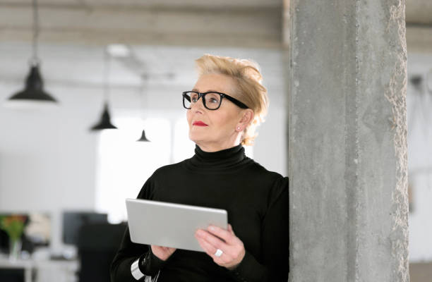 istock Elegant senior businesswoman using a digital tablet in the studio 810692792