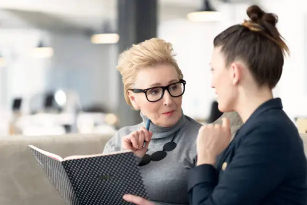 Photo of Senior adviser talking with young businesswoman