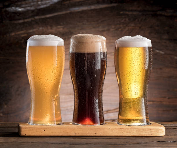 istock Three glasses of beer on the wooden table. 810734376