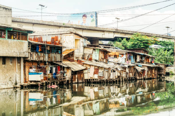 Slum Area in Jakarta, Indonesia Jakarta, Indonesia - October 31, 2016: Slum Area near polluted river under a bridge. Many people in Jakarta lives in slum areas, poverty is one of biggest problems in Jakarta city. jakarta slums stock pictures, royalty-free photos & images