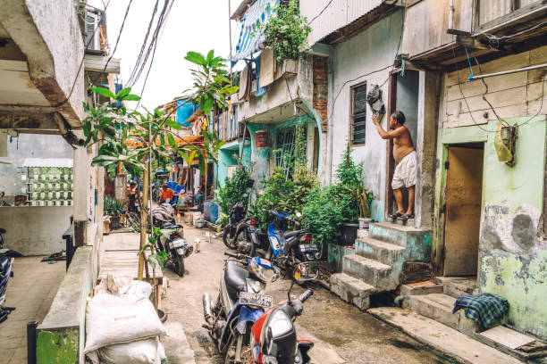 Jakarta Backstreet, Indonesia Jakarta, Indonesia - October 30, 2016: View of one of the alley in the outskirts of the giant city. People doing various activities. These poor neighborhood constitute the majority of the capital city. jakarta slums stock pictures, royalty-free photos & images