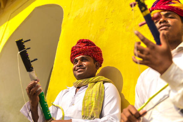 молодые индейцы играют на традиционном музыкальном инструменте в джайпуре, раджастан, индия - jaipur city palace стоковые фото и изображения