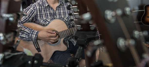 istock Young man playing the guitar in a shop 810782548