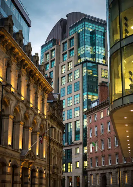 Illuminated office buildings in the English city of Manchester, with a mixture of old and new architecture.