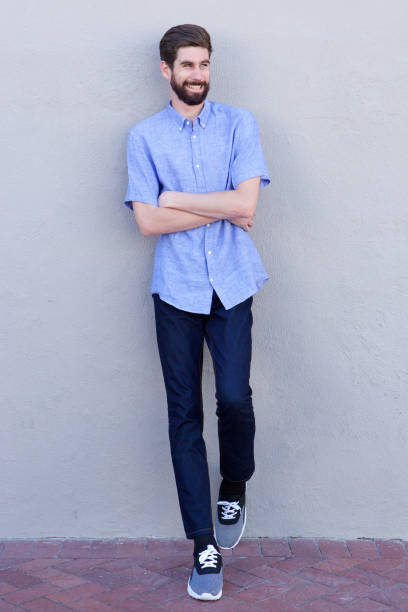 istock Full body smiling man leaning on wall with arms crossed 810797718