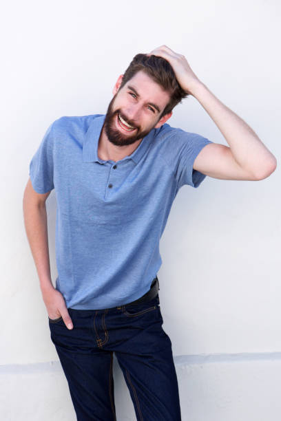 istock cheerful man laughing with hand in hair by white wall 810797840