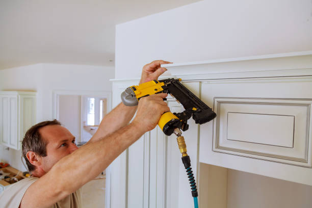 istock Carpenter brad using nail gun to Crown Moulding on kitchen cabinets framing trim, 810798504