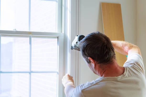 istock Carpenter using nail gun to moldings on windows, framing trim, 810798588