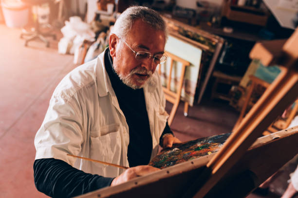 istock Old man artist painting oils in his studio. 810808148