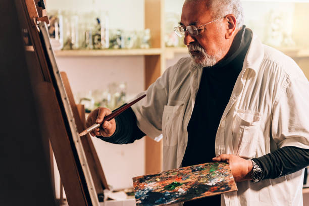 istock Old man artist painting oils in his studio. 810808166