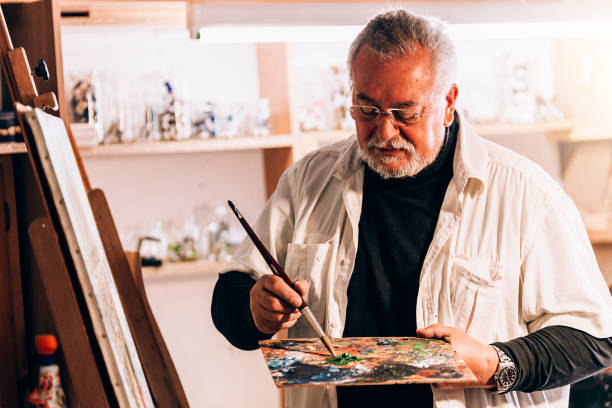 istock Old man artist painting oils in his studio. 810808184