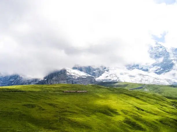 Swiss train during summer with alpine landscape in mountains in Interlaken with cloudy foggy mist