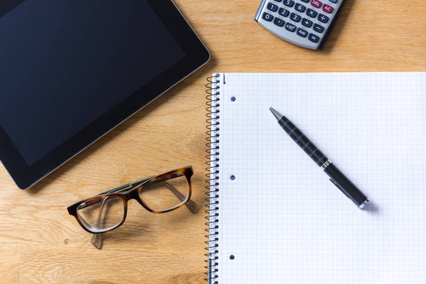 istock Work desk with tablet, glasses, calculator and notepad on wooden table from above 810850704