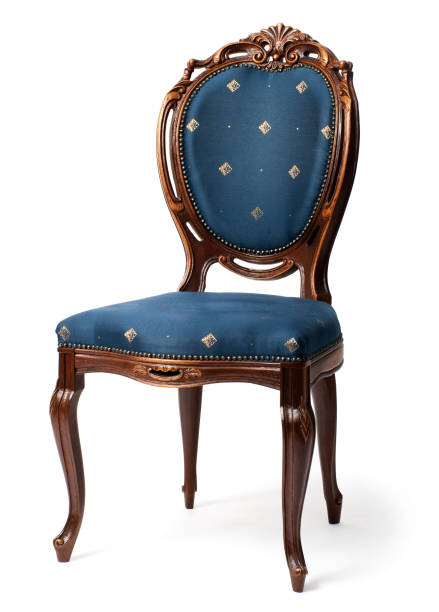 An ornate, wooden, antique-styled chair with heart-shaped backrest and a royal purple upholstery sits isolated against a white background.