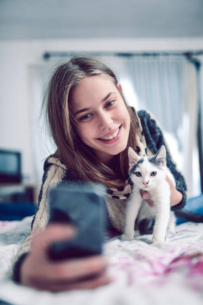 istock Cute Smiling Young Girl Taking Selfie with Cat 810922564