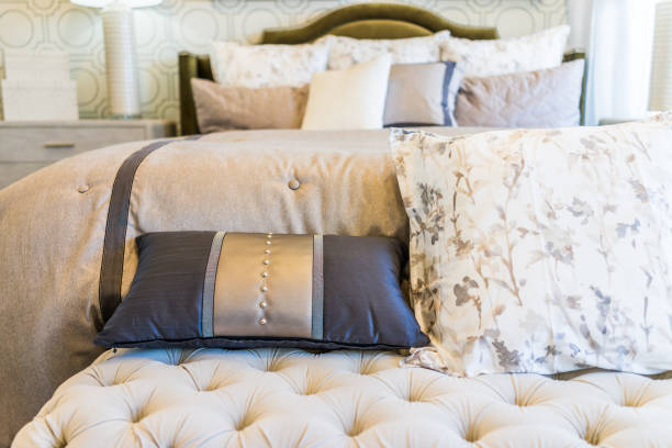 istock Modern decorated bed with bench rest and many pillows closeup 811030472