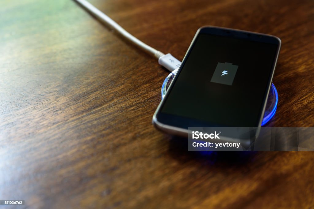 Smartphone charging on a charging pad. Wireless charging Smartphone charging on a charging pad. Wireless charging. Charging Stock Photo