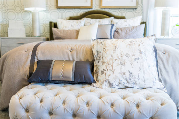 Modern decorated bed with bench rest and many pillows closeup