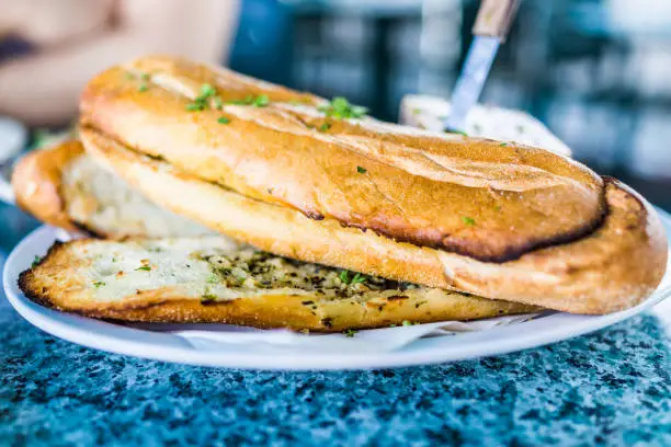 Macro closeup of large pieces of garlic bread in restaurant on plate with knife
