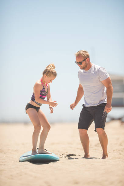 istock Athletic dad shows his daughters how to surf 811048452